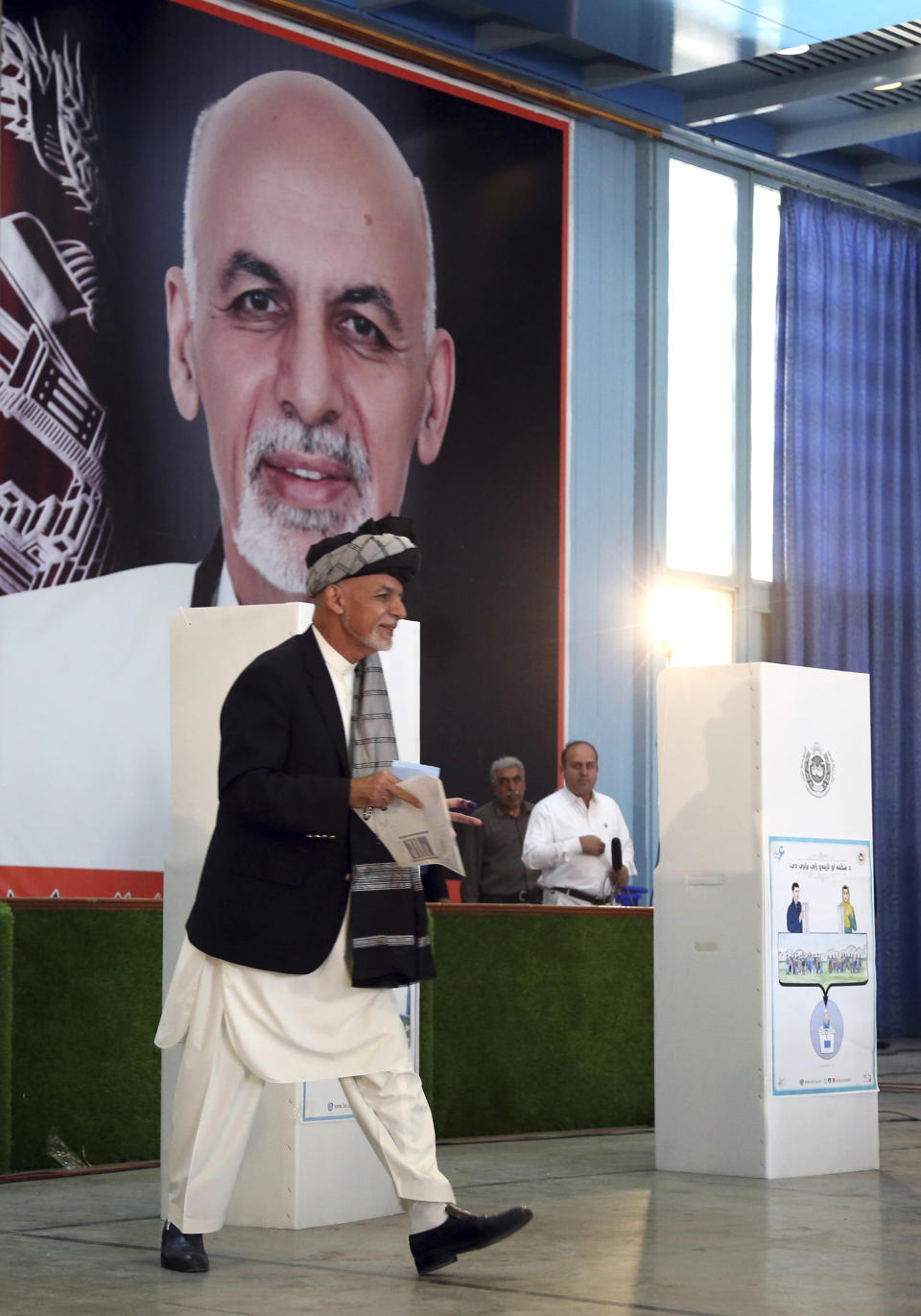 Afghan President Ashraf Ghani, center, walks to the ballot boxes before he casts his vote at Amani high school, near the presidential palace in Kabul, Afghanistan, Saturday, Sept. 28, 2019. Afghans headed to the polls on Saturday to elect a new president amid high security and Taliban threats to disrupt the elections, with the rebels warning citizens to stay home or risk being hurt. (AP Photo/Rahmat Gul)