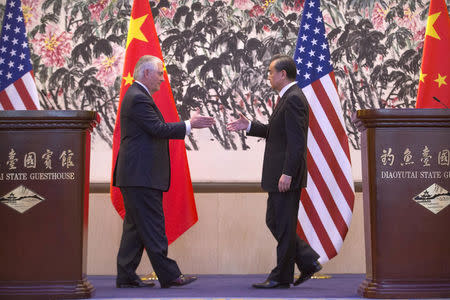 U.S. Secretary of State Rex Tillerson (L) and Chinese Foreign Minister Wang Yi (R) reach to shake hands at th end of a joint press conference at the Diaoyutai State Guesthouse in Beijing, China, March 18, 2017. REUTERS/ Mark Schiefelbein