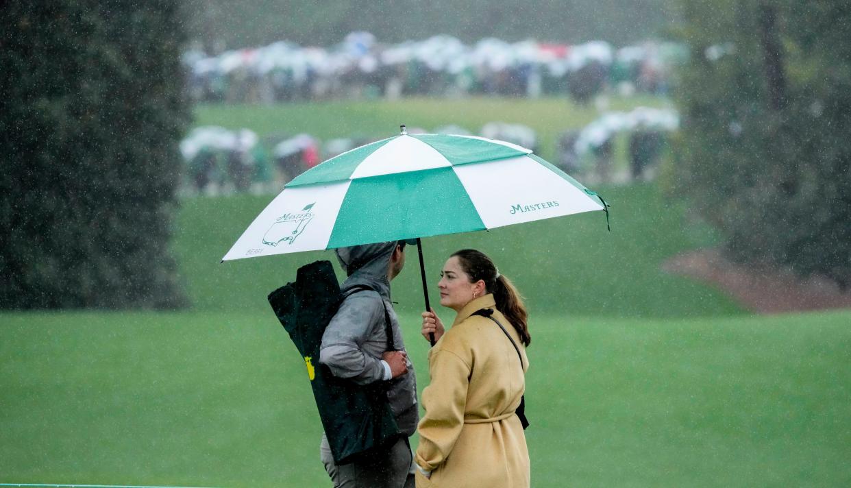 FILE - Apr 8, 2023; Augusta, Georgia, USA; Patrons stand under an umbrella as heavy rain falls on the course during the third round of The Masters golf tournament. Mandatory Credit: Rob Schumacher-USA TODAY Network