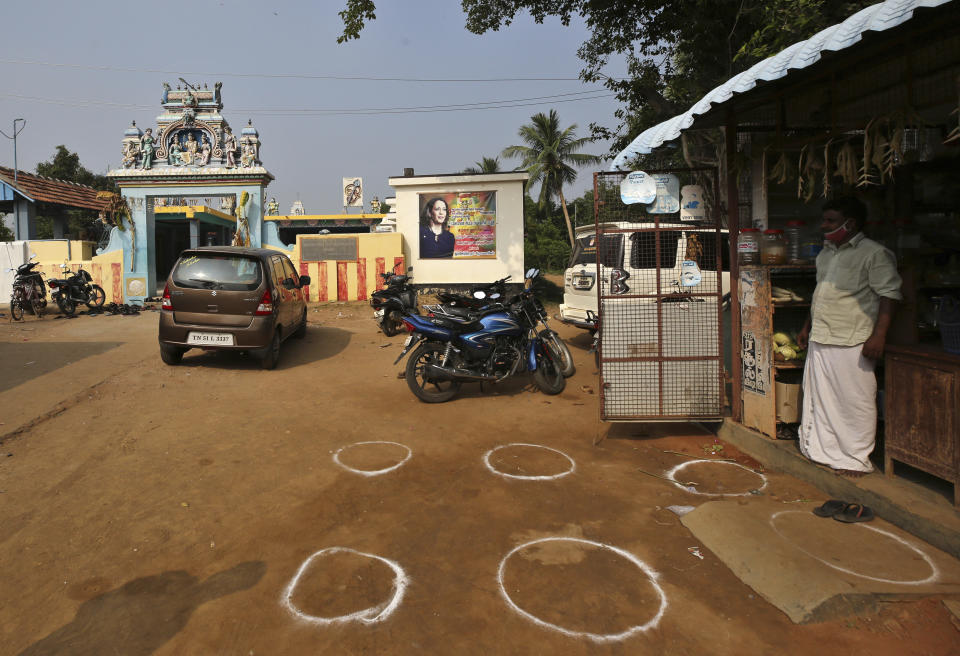 Markings are seen next to a grocery store for maintaining social distance outside a temple displaying a banner featuring U.S. democratic vice presidential candidate Sen. Kamala Harris in Thulasendrapuram village, south of Chennai, Tamil Nadu state, India, Tuesday, Nov. 3, 2020. The lush green village is the hometown of Harris’ maternal grandfather who migrated from there decades ago. (AP Photo/Aijaz Rahi)