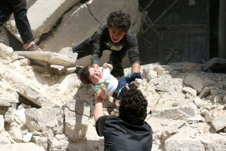 Syrians evacuate a toddler from a destroyed building following an air strike on a rebel-held neighbourhood of Aleppo