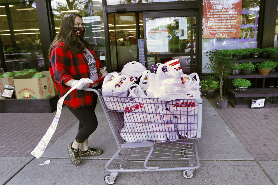 Alexandra Lopez-Djurovic heads to the parking lot with a long receipt trailing behind her after shopping for a client at an Acme supermarket, Wednesday, July 1, 2020, in Bronxville, N.Y. Lopez-Djurovic was working full time as a nanny until her hours were cut substantially amid the coronavirus pandemic, so she started her own grocery delivery service that made up for some of her lost wages, but not all. (AP Photo/Kathy Willens)