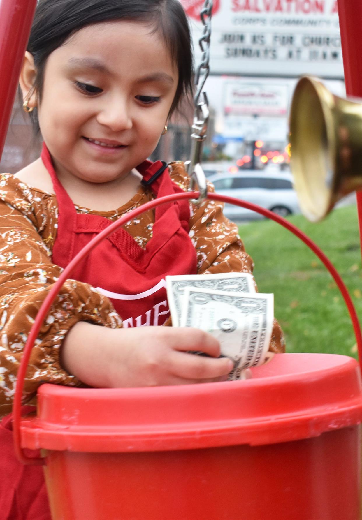 Abigail Parra puts money in The Salvation Army's kettle in Fall River, Mass., Monday Nov. 6, 2023. Representatives for The Salvation Army say holiday season kettle collections are receiving another high-tech upgrade this year, in hopes that a lack of cash on-hand won't stand in the way of willing donors.