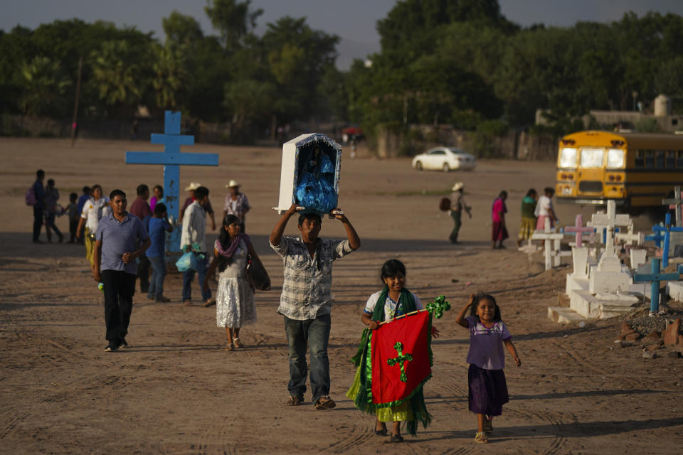 Una familia indígena yaqui camina junto al cementerio donde está enterrado Tomás Rojo _activista por la defensa del agua que fue asesinado_ frente a una iglesia a donde llegaron para celebrar a la Virgen María, el martes 27 de septiembre de 2022, en Potam, México. (AP Foto/Fernando Llano)