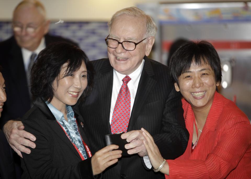 Billionaire financier and Berkshire Hathaway Chief Executive Warren Buffett (C) takes out his wallet to pose for a photo during his visit a new Dairy Queen store in Beijing September 30, 2010. REUTERS/Jason Lee 