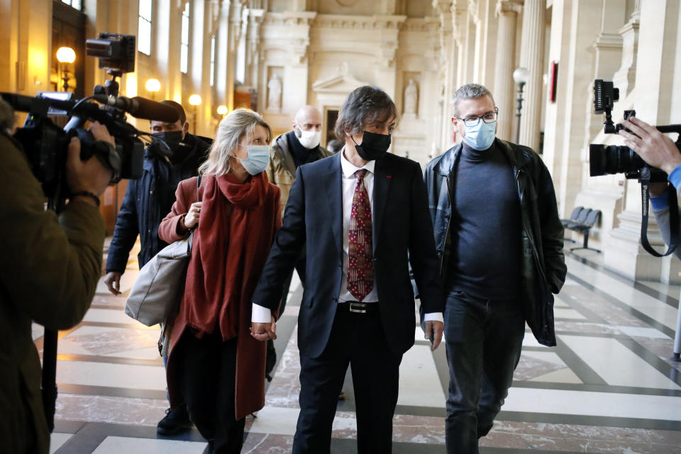 French-American Mark Moogalian, center, his wife Isabelle, left, and his lawyer Thibault de Montbrial, right, arrive at the Thalys attack trial, at the Paris courthouse, Thursday, Nov. 19, 2020. The lawyer for an American who was scheduled to testify about his role in the dramatic capture of an Islamic State operative aboard a high-speed train says his witness has been hospitalized after he flew in to Paris. (AP Photo/Francois Mori)