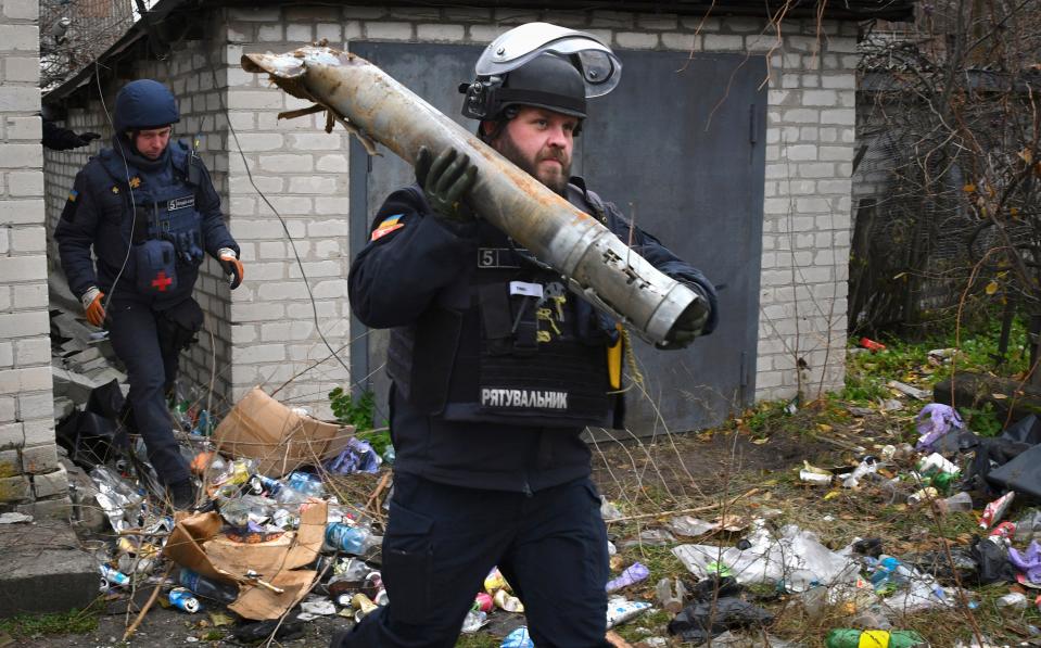 A Ukrainian sapper carries a part of a projectile in Lyman (AP)