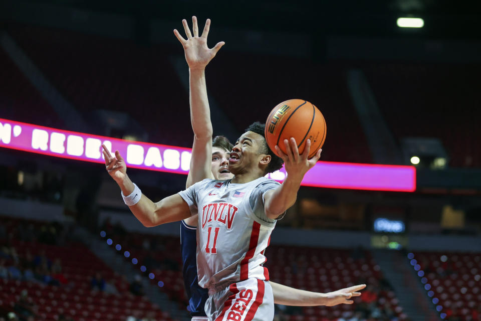 UNLV guard Dedan Thomas Jr. (11) drives past Utah State center Isaac Johnson (20) during the first half of an NCAA college basketball game Saturday, Jan. 13, 2024, in Las Vegas. (AP Photo/Ian Maule)