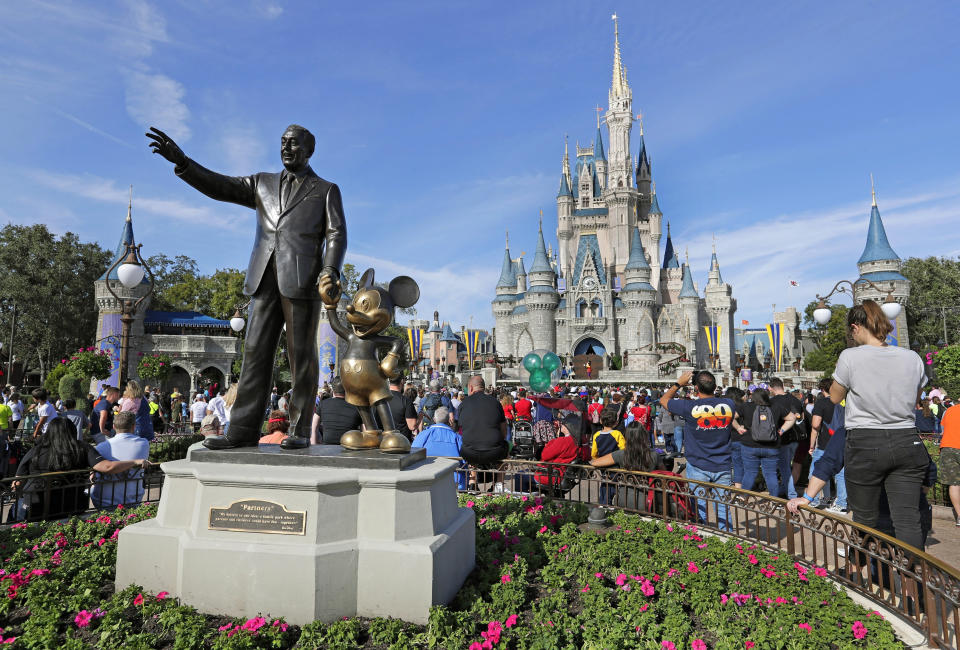 FILE - In this Jan. 9, 2019 photo, guests watch a show near a statue of Walt Disney and Micky Mouse in front of the Cinderella Castle at the Magic Kingdom at Walt Disney World in Lake Buena Vista, Fla. The Walt Disney Company reports their corporate results on Wednesday, Feb. 8, 2023. . (AP Photo/John Raoux)