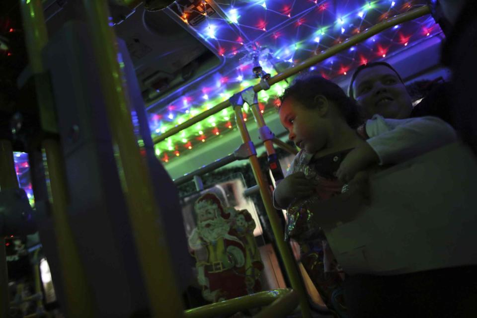 Mother with her daughter enter an urban bus decorated with Christmas motives while the bus driver Edilson, also known as "Fumassa", drives it in Santo Andre