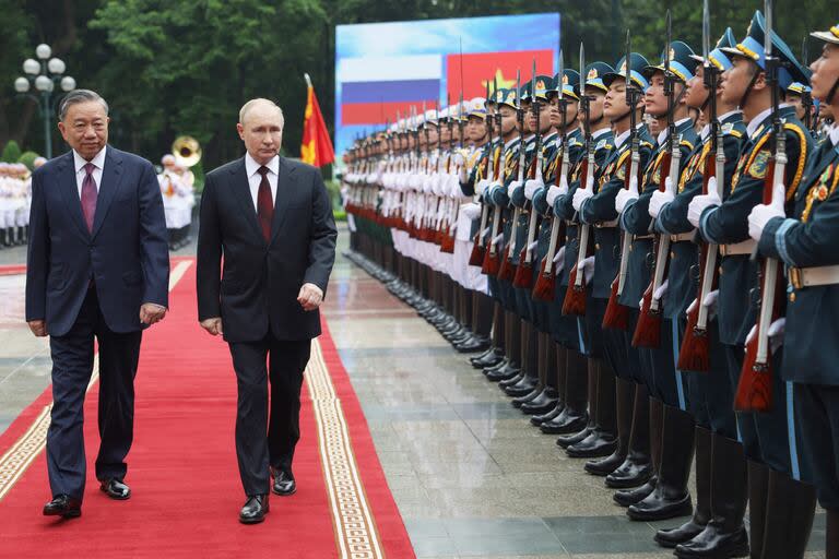 En esta fotografía de grupo distribuida por la agencia estatal rusa Sputnik, el presidente de Rusia, Vladímir Putin  y el presidente de Vietnam, To Lam, llegan para una ceremonia de bienvenida fuera del Palacio Presidencial en Hanoi el 20 de junio de 2024.