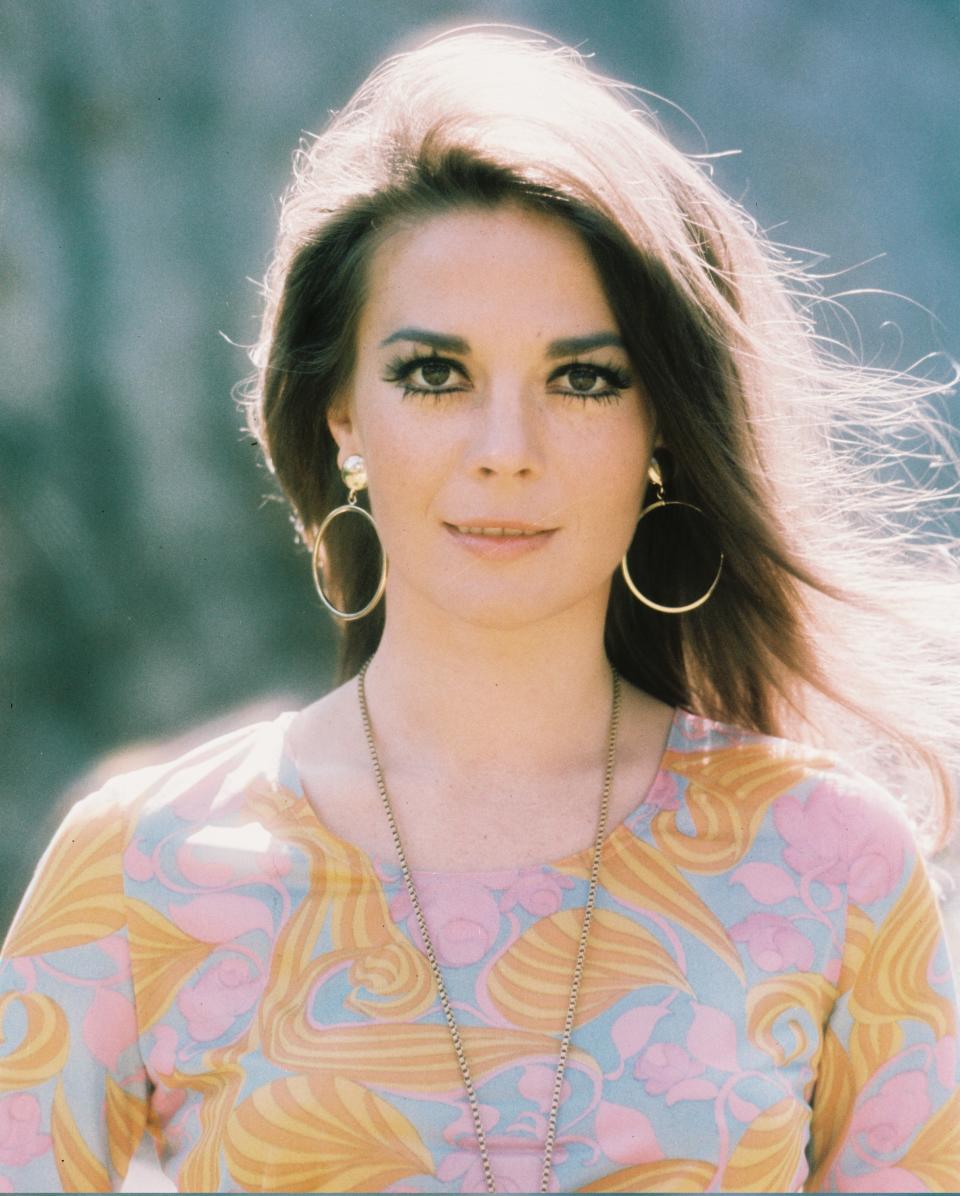 Natalie Wood, wearing a 70s style orange, pink and blue top and hoop earrings