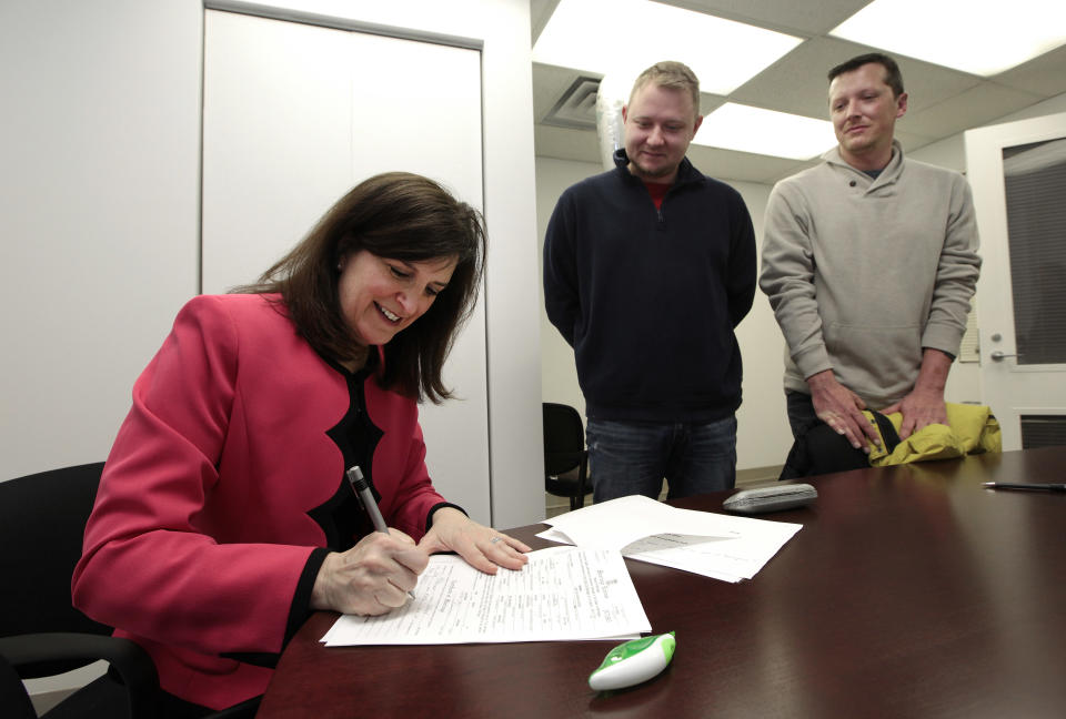 Oakland County Clerk Lisa Brown signs a marriage license for Justin Flowers, middle, and Josh Redder after performing their wedding ceremony at the Oakland County Clerks office in Pontiac, Mich., Saturday, March 22, 2014. A federal judge has struck down Michigan's ban on gay marriage Friday the latest in a series of decisions overturning similar laws across the U.S. Some counties plan to issue marriage licenses to same-sex couples Saturday, less than 24 hours after a judge overturned Michigan's ban on gay marriage. (AP Photo/Paul Sancya)