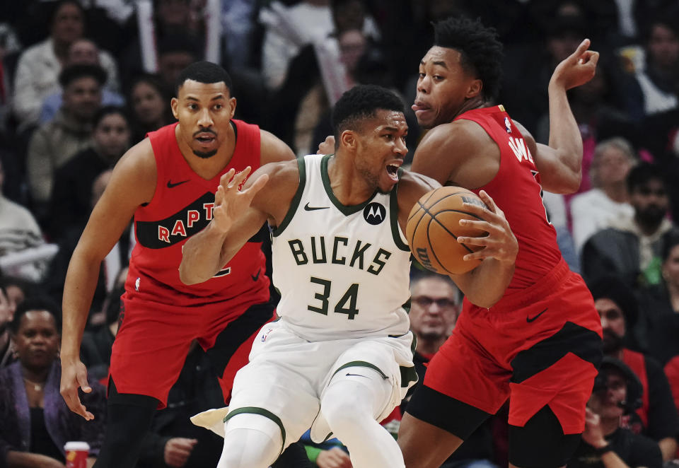 Milwaukee Bucks forward Giannis Antetokounmpo (34) protects the ball as Toronto Raptors forward Otto Porter Jr., left, and forward Scottie Barnes defend during the second half of an NBA basketball game Wednesday, Nov. 1, 2023, in Toronto. (Nathan Denette/The Canadian Press via AP)