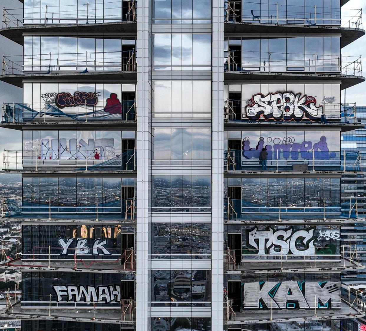 Taggers are seen on upper floors of an unfinished building.