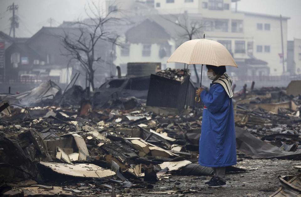 A woman looks at the burned-out marketplace by a fire following earthquakes in Wajima, Ishikawa prefecture, Japan Wednesday, Jan. 3, 2024. (Kyodo News via AP)