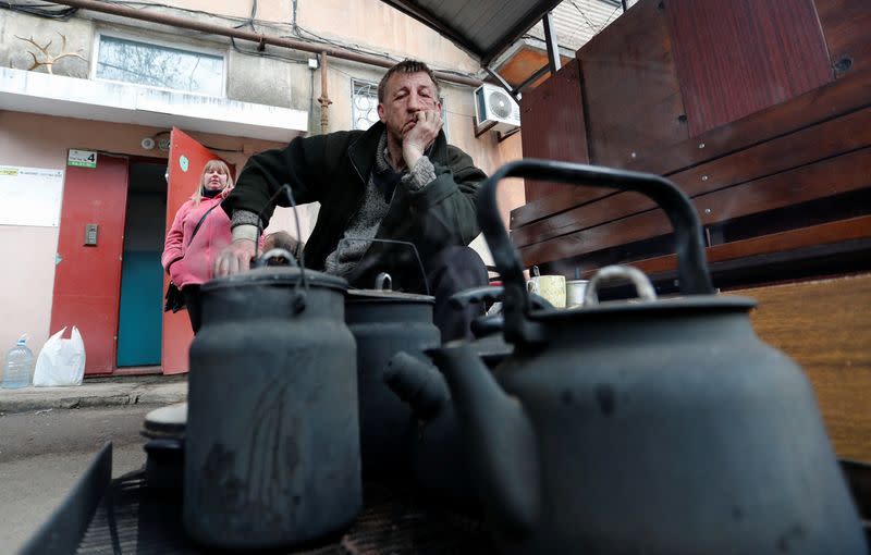 A local resident cooks food in a courtyard in Mariupol