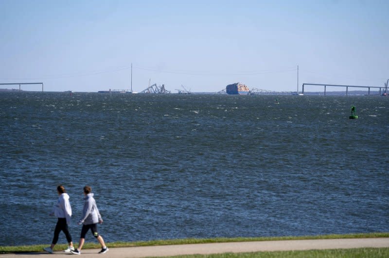 People on shore view the Dali cargo vessel and what remains of the the Francis Scott Key Bridge in Baltimore, Md., on Friday. Photo by Bonnie Cash/UPI