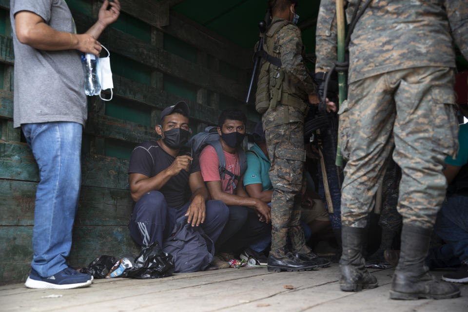 Honduras migrants sit in an army truck before return home, in Morales, Guatemala, Saturday, Oct. 3, 2020. Early Saturday, hundreds of migrants who had entered Guatemala this week without registering were being bused back to their country's border by authorities after running into a large roadblock. (AP Photo/Moises Castillo)