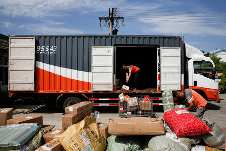 FILE PHOTO: Workers unload parcels from a truck at a distribution hub of the Chinese delivery company Shentong (STO) Express in Beijing, China, August 29, 2017. REUTERS/Thomas Peter/File Photo