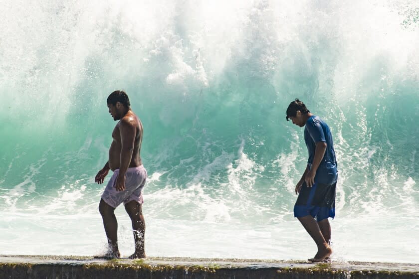 Dos personas caminan frente a olas elevadas cerca de Kapahulu Groin (muro de Waikiki) el domingo 17 de julio de 2022, en Waikiki, Hawai. (Craig T. Kojima/Honolulu Star-Advertiser vía AP)