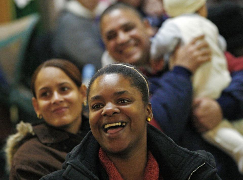 People smile as they find out that Secret Santa, a wealthy philanthropist from Kansas City, Mo., will be handing them $100 dollar bills at St. Joseph's Social Service Center and other locations in Elizabeth, N.J., Thursday, Nov. 29, 2012. Secret Santa distributed the money to the needy at St. Joseph's as well as other locations in Elizabeth. (AP Photo/Rich Schultz)