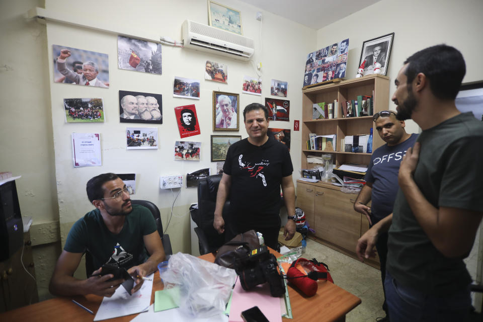 In this Thursday, Aug. 29, 2019 photo, an activist takes a photo of Ayman Odeh, center, the leader of the Arab Joint List parties, talks to activists at campaign office in Nazareth, Israel. Odeh has shaken up Israel's election campaign by offering to sit in a moderate coalition government _ a development that would upend decades of convention that has relegated Arab parties to the sidelines and could bring down Prime Minister Benjamin Netanyahu. (AP Photo/Mahmoud Illean)