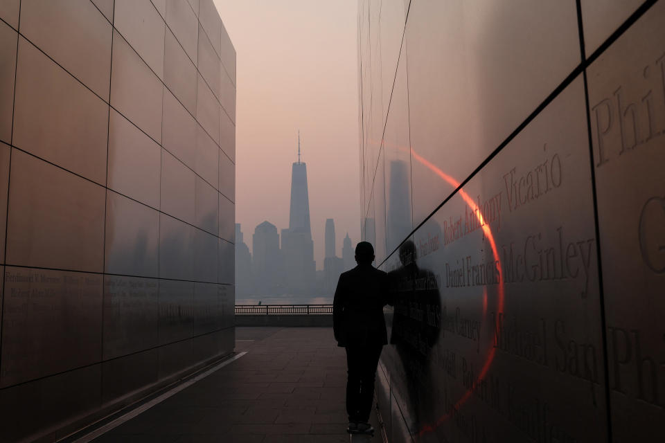 A man stands in the Empty Sky 911 Memorial in Jersey City, New Jersey looking towards the One World Trade Center tower in lower Manhattan as haze and smoke caused by wildfires in Canada hangs over the skyline, June 8, 2023. (Mike Segar/Reuters)