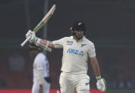 New Zealand's Tom Latham raises his bat after scoring fifty runs during the day two of their first test cricket match with India in Kanpur, India, Friday, Nov. 26, 2021. (AP Photo/Altaf Qadri)