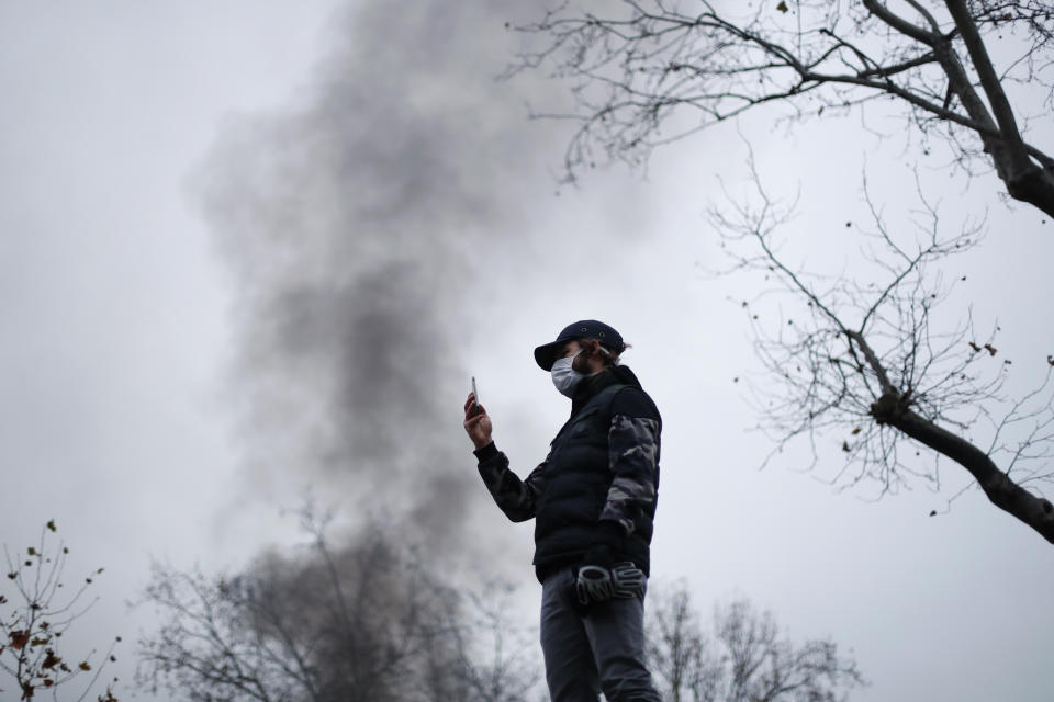 A demonstrator takes snapshots during a demonstration in Paris, Thursday, Dec. 5, 2019. The Eiffel Tower shut down, France's high-speed trains stood still and tens of thousands of people marched through Paris and other cities Thursday, in a massive and sometimes chaotic outpouring of anger at the government's plan to overhaul the retirement system. (AP Photo/Thibault Camus)