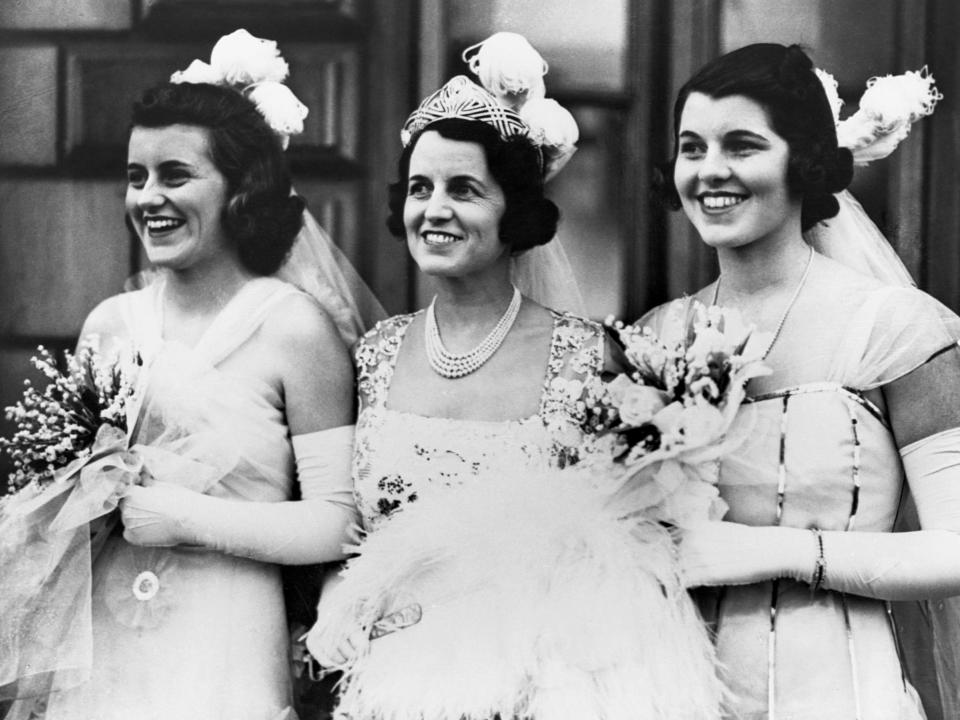 Kathleen, Rose, and Rosemary Kennedy in formal gowns and carrying bouquets at Buckingham Palace in 1938.