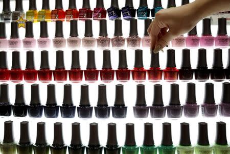 A shop clerk adjusts a bottle of manicure displayed at an exhibition and sale during Tokyo Nail Expo 2015 in Tokyo, REUTERS/Yuya Shino