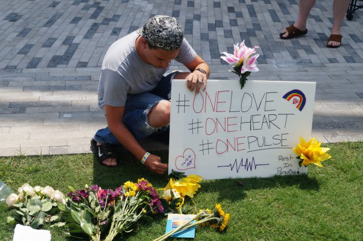 Josh Mercer, of Orlando, Fla., places a poster for his friend at a memorial outside the Dr. Phillips Center for the Performing Arts in Downtown Orlando on June 13, 2016. (Photo: Michael Walsh/Yahoo News)