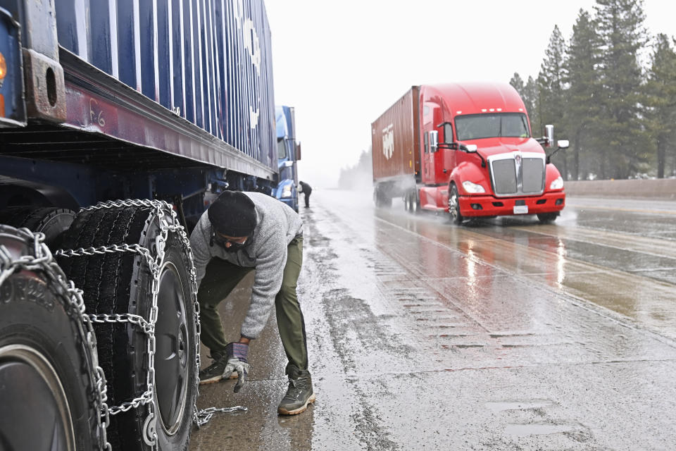 Mangal Singh parks his truck off the I-80 to put chains on his truck wheels in preparation for the snow storm over the Sierra Nevada on Thursday, Feb. 29, 2024, in Truckee, Calif. A Pacific storm packing powerful winds and heavy snow is shaping up to be the strongest of the season, forecasters say. (AP Photo/Andy Barron)