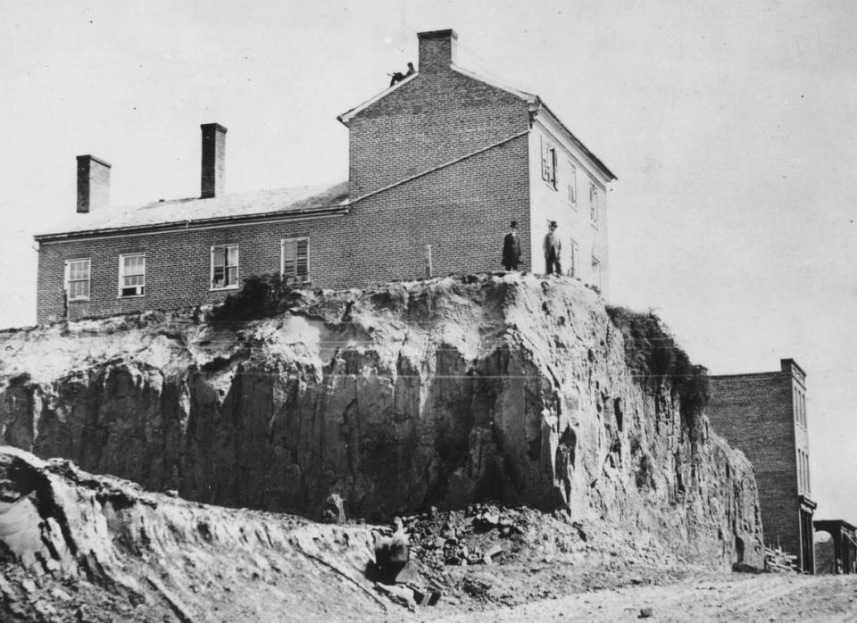 A house was perched well above street level in 1868 after road work leveled the grade on Main. Notice the person relaxing to the left of the chimney.