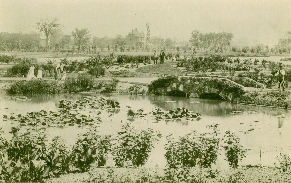 This photo was taken in Washington Park in 1895, just a few years after the park came into being. A lily pond and stone bridge are in the foreground, with a building and wind turbine in the background. Several people can be seen enjoying the park.
(Photo: Historic Photo Collection/Milwaukee Public Library)