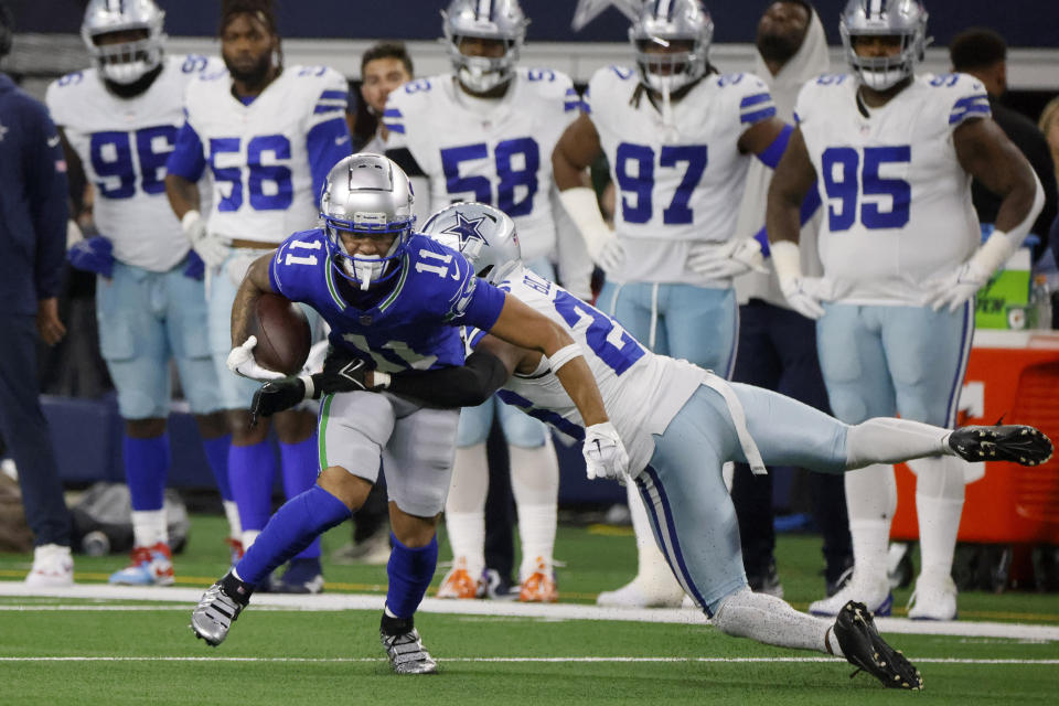 Seattle Seahawks wide receiver Jaxon Smith-Njigba (11) works for extra yardage after catching a pass as Dallas Cowboys cornerback DaRon Bland (26) makes the stop in the first half of an NFL football game in Arlington, Texas, Thursday, Nov. 30, 2023. (AP Photo/Michael Ainsworth)