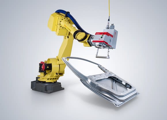 Yellow robotic arm holding laser and metal car door frame.