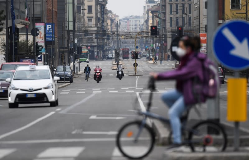 An unusually empty avenue is seen as a person wearing a face mask rides a bike, amid concerns about the spread of coronavirus disease (COVID-19), in Milan