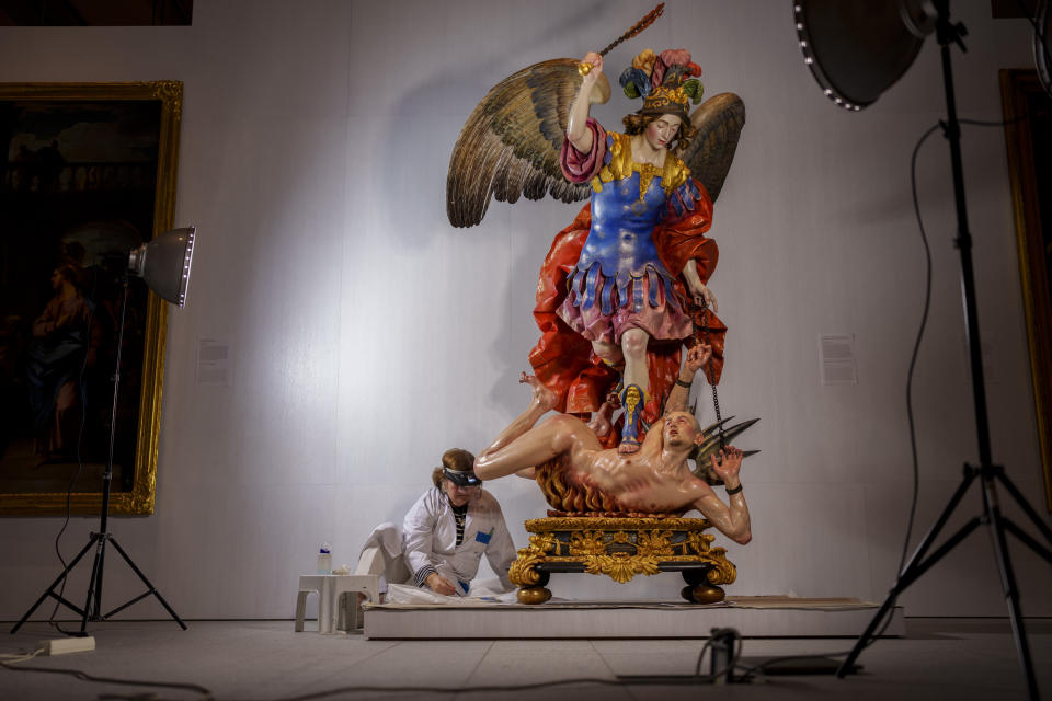 Restorer Ana Maria Loureiro Arias works on the Religious sculpture called "Saint Michael Slaying the Devil", at the Royal Collections Gallery in Madrid, Spain, Friday, May. 19, 2023. Spain is set to unveil what is touted as one of Europe’s cultural highlights of the year with the opening in Madrid of The Royal Collections Gallery next month. (AP Photo/Manu Fernandez)