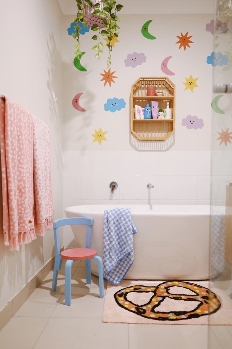 white kids bathroom with colorful wall decals and small chair