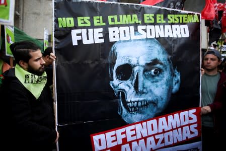 Demonstrators hold a placard with a skull and the face of Brazilian President Jair Bolsonaro that reads "it isn't the weather, it's the system. It was Bolsonaro", during a protest outside the Brazilian embassy due to the wildfires in the Amazon rainforest,