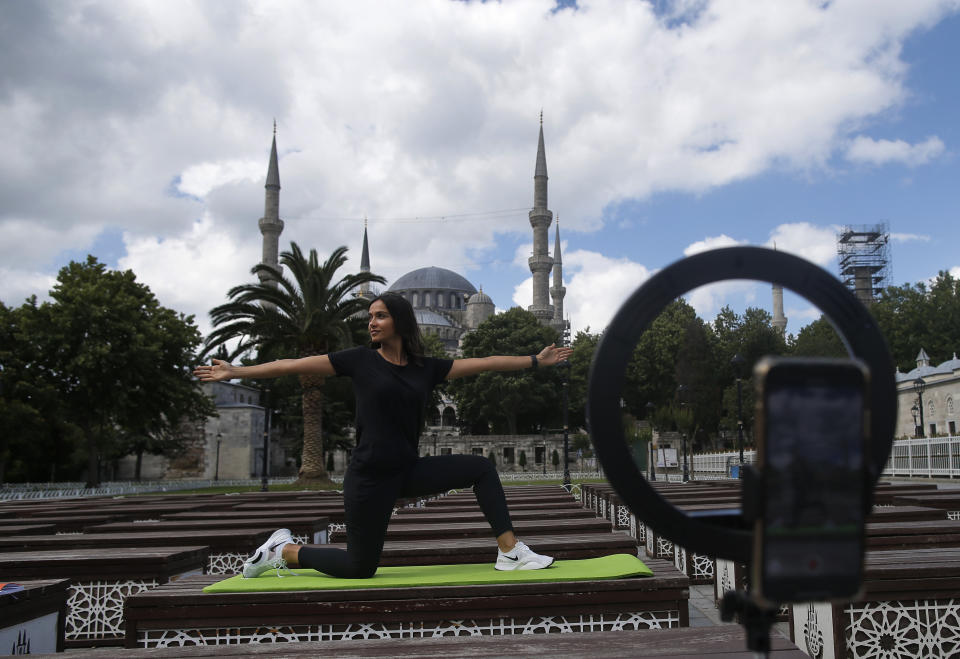 Yoga instructor Anil Altuntas broadcasts a live lesson to her students outside the iconic Sultan Ahmed Mosque, better known as the Blue Mosque, on the historic Sultanahmet district in Istanbul, Friday, July 10, 2020. (AP Photo/Emrah Gurel)