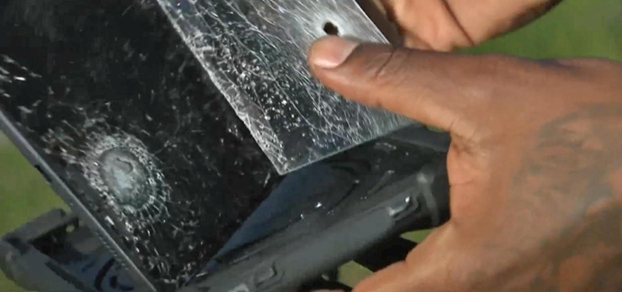 The door-to-door salesman shows  where a bullet hit his tablet. (NBCDFW)