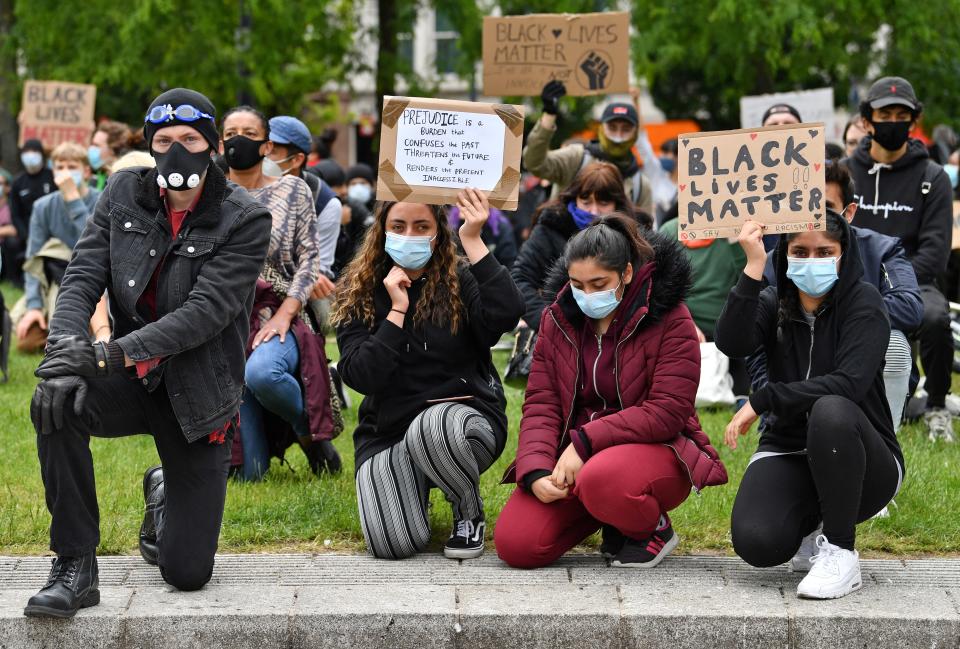 Protesters, some wearing PPE (personal protective equipment), including a face mask as a precautionary measure against COVID-19,  kneel as they hold placards during a demonstration in Manchester, northern England, on June 6, 2020, to show solidarity with the Black Lives Matter movement in the wake of the killing of George Floyd, an unarmed black man who died after a police officer knelt on his neck in Minneapolis. - The United States braced Friday for massive weekend protests against racism and police brutality, as outrage soared over the latest law enforcement abuses against demonstrators that were caught on camera. With protests over last week's police killing of George Floyd, an unarmed black man, surging into a second weekend, President Donald Trump sparked fresh controversy by saying it was a "great day" for Floyd. (Photo by Paul ELLIS / AFP) (Photo by PAUL ELLIS/AFP via Getty Images)