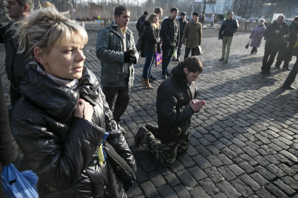 A man kneels as he pays his respects to fallen anti-Yanukovich protesters near Kiev's Independence Square