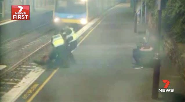 The woman is pulled to safety, just metres ahead of the train. Picture: 7 News