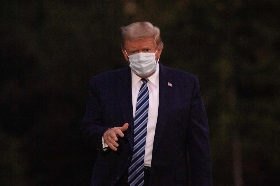 US President Donald Trump gestures to the press as he arrives at the White House wearing a facemask upon his return from Walter Reed Medical Center, where he underwent treatment for Covid-19, in Washington, DC, on October 5, 2020. (Photo by NICHOLAS KAMM / AFP) (Photo by NICHOLAS KAMM/AFP via Getty Images)