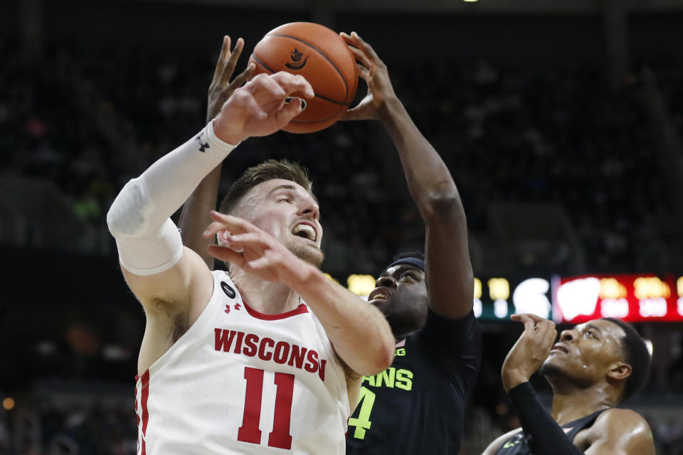 Michigan State forward Gabe Brown, center, grabs a rebound next to Wisconsin forward Micah Potter (11) during the first half of an NCAA college basketball game, Friday, Jan. 17, 2020, in East Lansing, Mich. (AP Photo/Carlos Osorio)