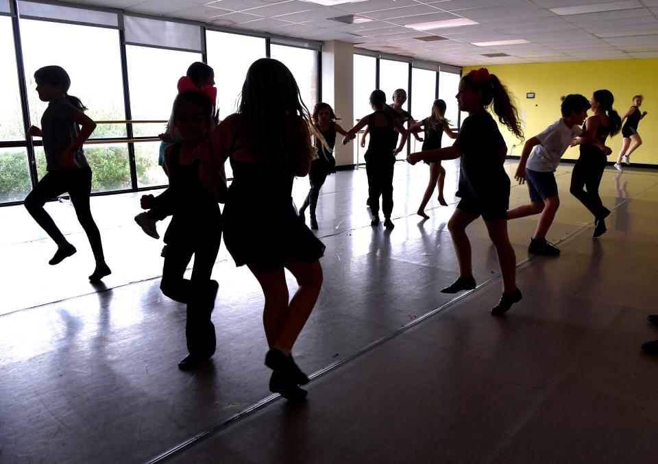 Students at the Abilene Performing Arts Company are silhouetted Tuesday against windows as they rehearse for this weekend's show, which begins at  2:30 p.m. Saturday at the Abilene Convention Center.